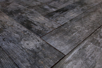 Modern vinyl floor with old wood imitation. Close-up of new gray flooring with texture from tiles with brown grains and knots. Decorative background of wooden boards.