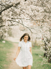 A young woman walks among the blossoming garden.