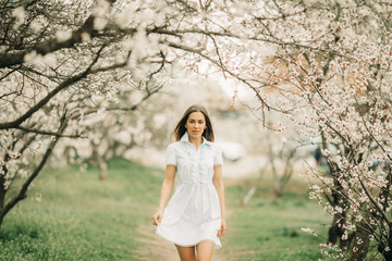 A young woman walks among the blossoming garden.