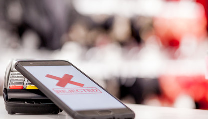 Fototapeta premium POS terminal, Payment Machine with mobile phone on store background. Contactless payment with NFC technology