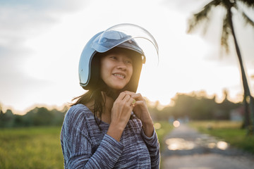 asian young woman wearing helmet fasten before motorcycling