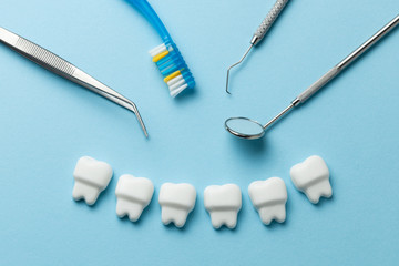 Healthy white teeth on blue background and dentist tools mirror, hook.