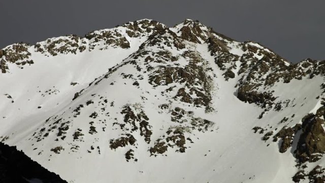 A steady, medium shot of the top of a mountain being almost completely camouflaged by the snow.