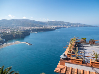 Fototapeta premium Amazing aerial view of coastline Sorrento city and Gulf of Naples - popular tourist destination in Italy. Sunny summer day with blue sky, clear sea and green mountains. Italy, april 2019