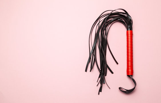Leather whip on pink background. Sex toy for intimate perversions. Sex slavery