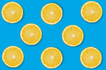 Obraz premium Horizontal rows of circles slices of fresh ripe oranges with pulp and peel on blue table on kitchen with copy space for your text. Top view. Concept of prepare of vegetarian food. Seamless pattern