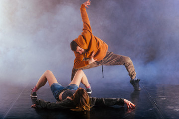 The beautiful female dancer is laying on the floor while her male partner performs an exotics unique modern art moves over her.