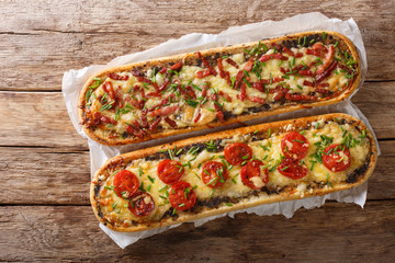 Hot sandwiches with bacon, mushrooms, tomatoes and cheese close-up on parchment. Horizontal view top