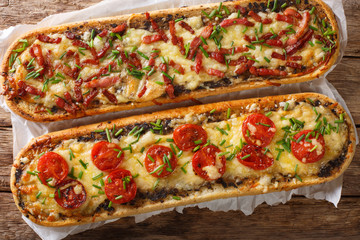 Close-up pizza sandwiches with bacon, mushrooms, tomatoes and cheese on a parchment. Horizontal...