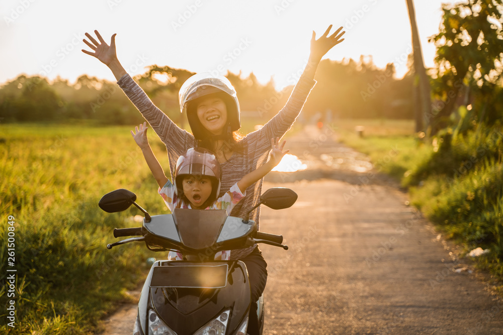 Wall mural mom and her child enjoy riding motorcycle scooter in country ride road