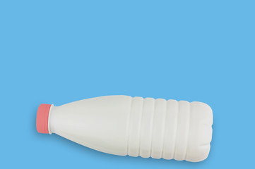 Fresh dairy product in full plastic bottle for milk, kefir or yoghurt with red cap on blue table on...