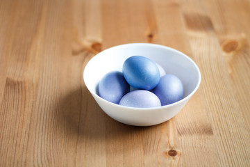 painted purple eggs in a plate on a light Easter background
