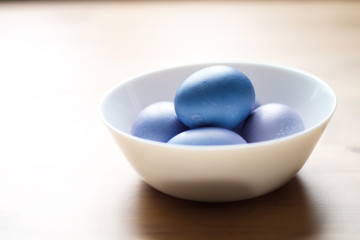 painted purple eggs in a plate on a light Easter background