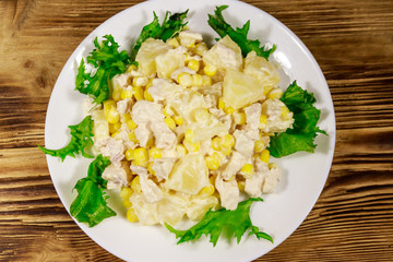 Festive salad with chicken breast, sweet corn, canned pineapple and mayonnaise on wooden table
