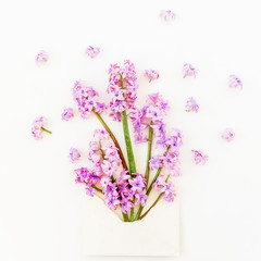Beauty blog concept. Bouquet of pink flowers, petals and envelope on white background. Flat lay, top view.