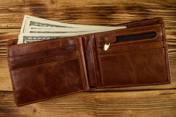 Opened wallet with american dollars on wooden table. Top view