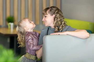 Young mother with a small daughter in a cafe. Beautiful Caucasian mother daughter a girl of 4-5 years of age sitting in a cafe.