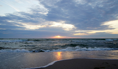 Summer evening sunny sunset in the sea on the shore. Sandy coast on the ocean.