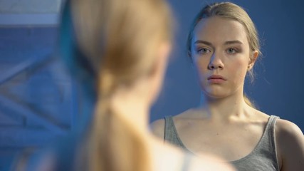 Shocked female looking underarm in mirror reflection, puberty age, body changes