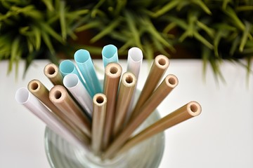 Natural bamboo and plastic straws in glass, alternative choice, zero waste, no plastic concept.