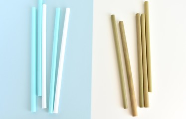 Choice between one time use plastic straw and natural bamboo straw, flat lay on white blue background, zero waste, no plastic concept.