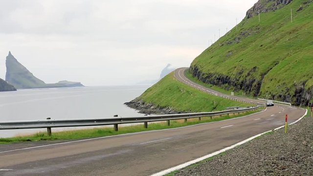 Real-time footage of a car driving fast along the freeway in the Scottish highlands. Motorway by the sea with blue sky and clouds over a rural countryside. Skye Island in Scotland.