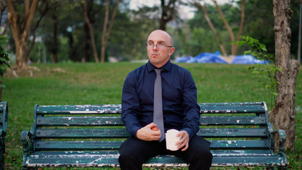 Fototapeta premium Office Worker On Break Drinking Coffee And Eating Apple While Sitting on Bench Outside