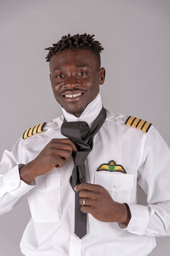 London,UK. April 2019.  A young airline pilot with an african dred hairstyle. Crew member tying his black tie,