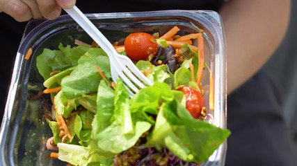 Putting Healthy Sunflower Seeds on Fresh Salad in Plastic Container and Then Mixing With Fork