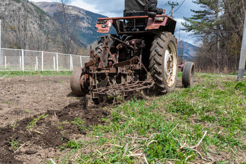 old small tractor harrow field in spring, Caucasus. Karachay-Cherkessia Russia
