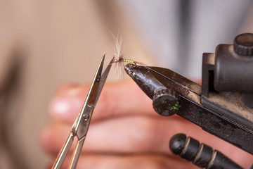 Close up of fisherman tying a fly for fishing .