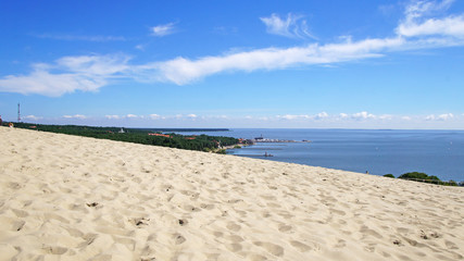 Fototapeta na wymiar Sandy beach and dunes near the sea and bright blue sky. Sunny summer day.