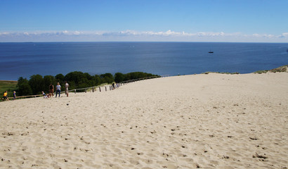 Sandy beach and dunes near the sea and bright blue sky. Sunny summer day.