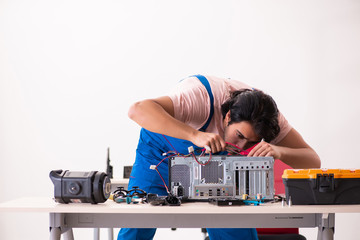 Young male contractor repairing computer  