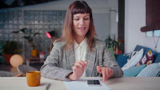 Portrait of emotional elegant business female working on mobile phone device, spend leisure time at work place, dressed in suit and shirt, achieve entrepreneur's goals, making a hand gesture