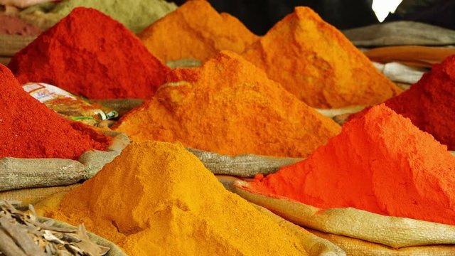 A panning, close up shot of raffia bags full with powdery spices.