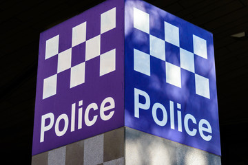A two sided blue and white police sign with chequered police pattern