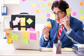 Young male handsome employee in conflicting priorities concept 