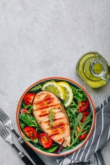 Grilled salmon steak with fresh green arugula salad and tomatoes