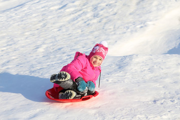 Fototapeta na wymiar girl riding on snow slides in winter time