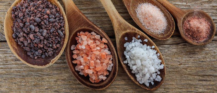 Salts variation crystals and powder in wooden spoons and background, banner