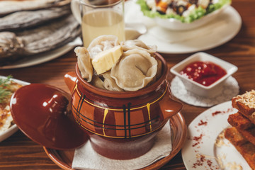Dumplings in a clay pot with sour cream