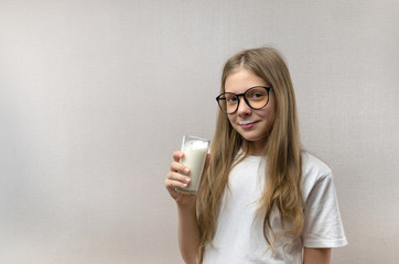 Portrait of a little happy girl with glasses and a glass of milk. Milkshake. Healthy food. Healthy breakfast