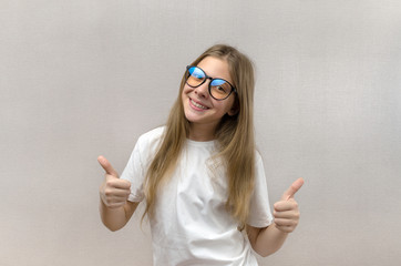 Portrait of a blonde girl with glasses that shows thumbs up. Sign of approval and consent