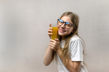 Blonde happy girl holds in her hand a glass of fresh juice. Healthy diet. Veggie and vegan.