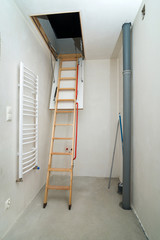 Wooden ladder to attic. Unfinished building interior