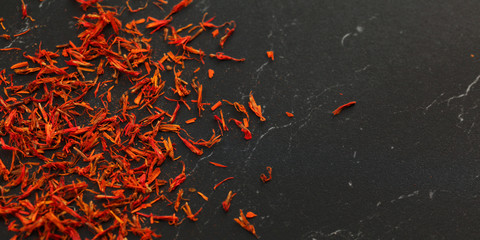 Saffron crocus crimson stigmata and styles threads used as spice, on black marble like working...