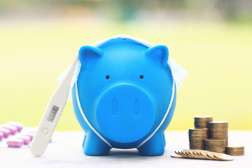 Blue piggy with thermometer and medicine on natural green background,Save money for Medical expenses and Health care concept