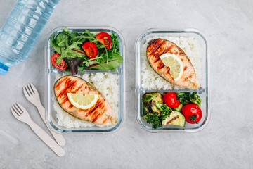 Meal prep containers with salmon and rice, green salad and baked vegetables.