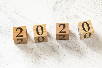 Four wooden cubes with number 2020 on white working board.